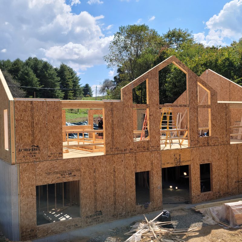 Structural insulated panel (SIP) installation during framing phase of energy-efficient mountain home, showing engineered wall and floor system layout