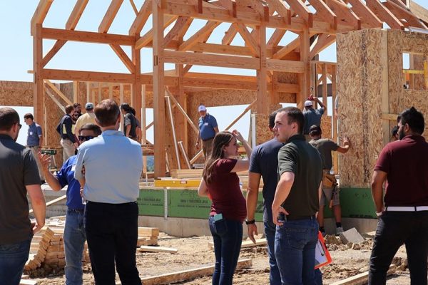 Pinnacle Engineering team conducts a site visit at a residential timber-frame construction project in Ohio, reviewing progress and structural details under clear blue skies.