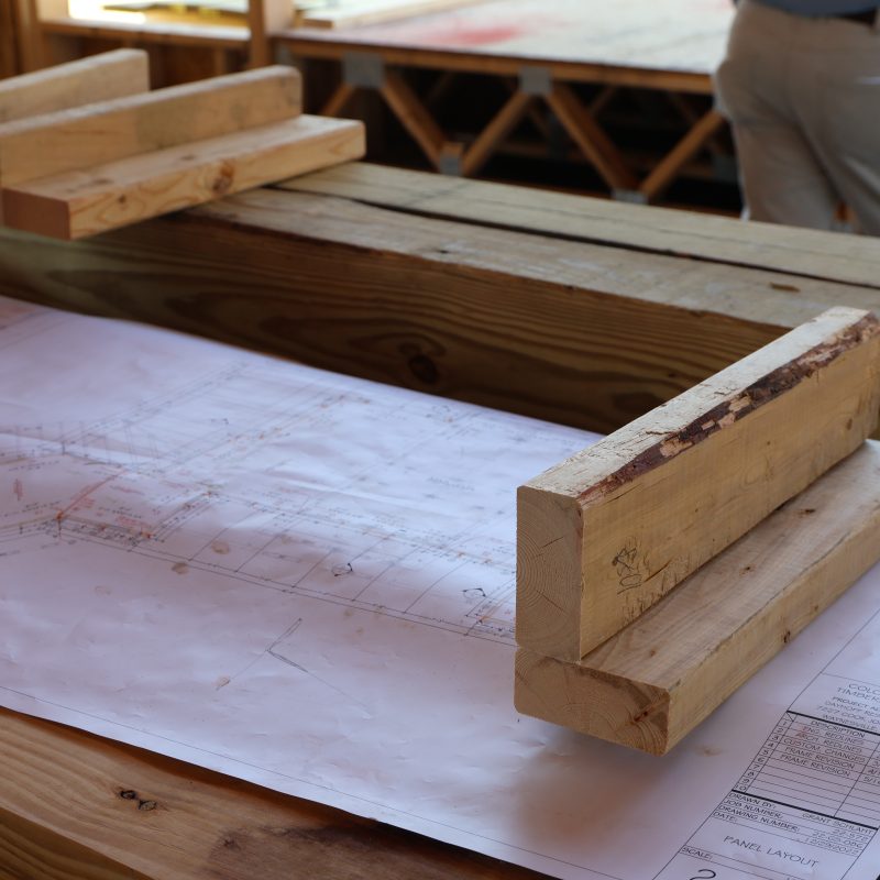 Structural engineering and architect Custom Residential Home blueprints held down by lumber at a commercial construction site