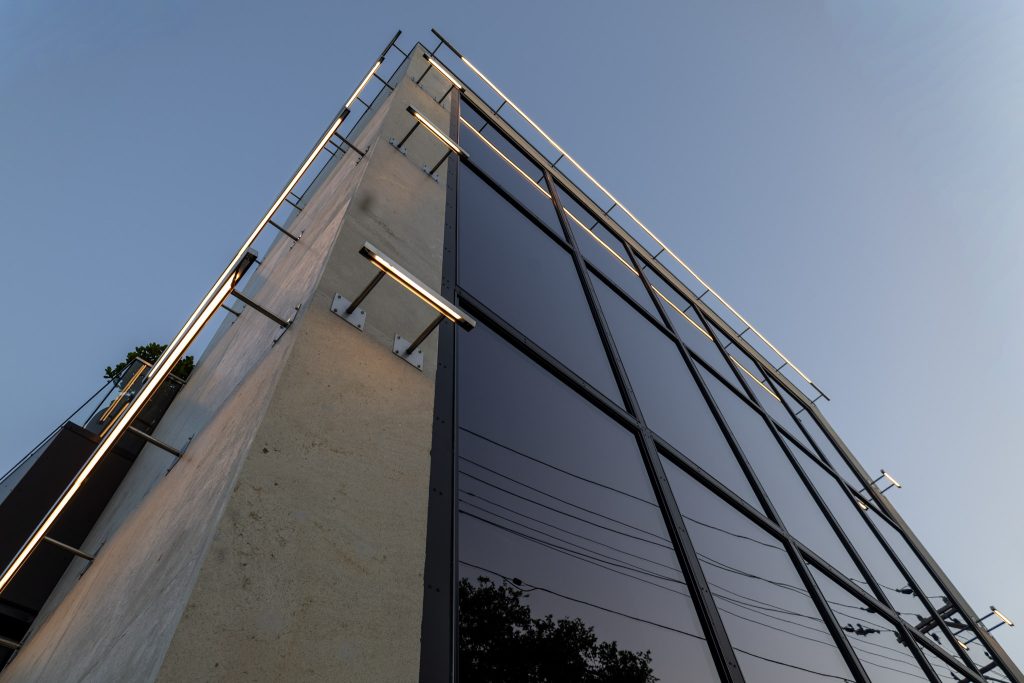 IMG_9927 upward view of the Fotofocus building facade in Cincinnati, Ohio, showing the concrete corner wall, dark glass curtain wall with steel framing, and projecting linear light fixtures