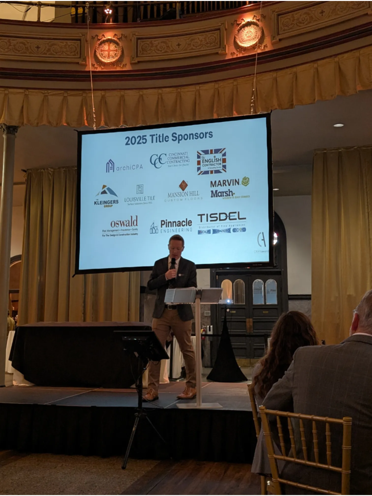 Speaker at the podium with 2025 AIA Cincinnati CRANawards sponsor screen displaying Pinnacle Engineering among the title sponsors.