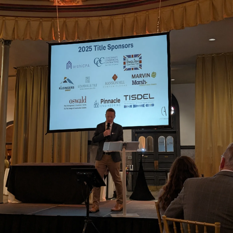 Speaker at the podium with 2025 AIA Cincinnati CRANawards sponsor screen displaying Pinnacle Engineering among the title sponsors.