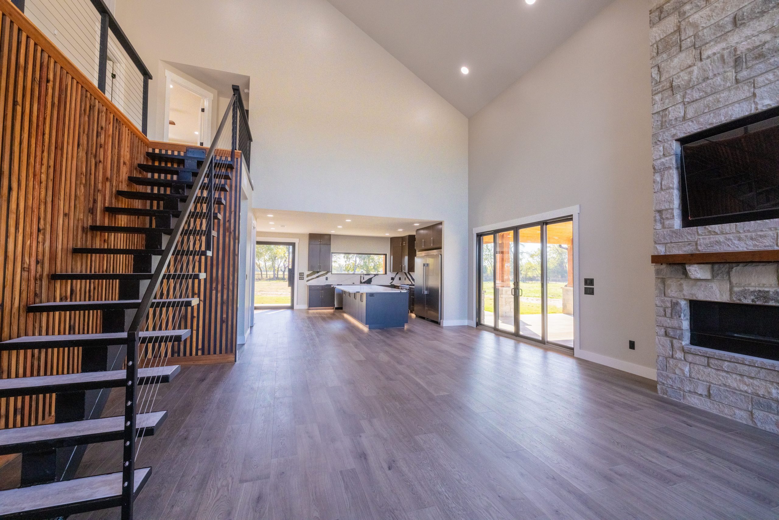 barndominium interior open floor plan with vaulted ceilings staircase and stone fireplace